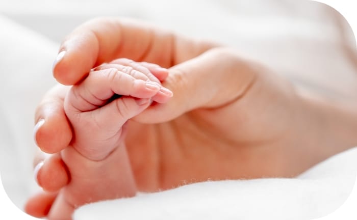 The soft grasp of a baby’s hand held lovingly by mom